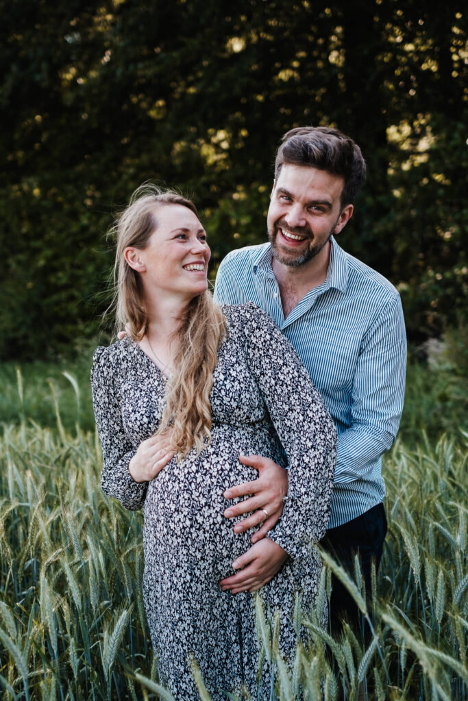 Babybauchfoto einer schwangeren Frau mit ihrem Mann im Kornfeld