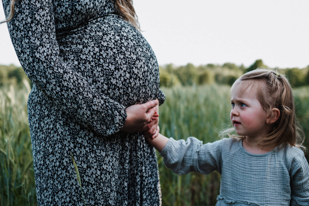 Babybauch Foto close up im Kornfeld mit Geschwisterkind