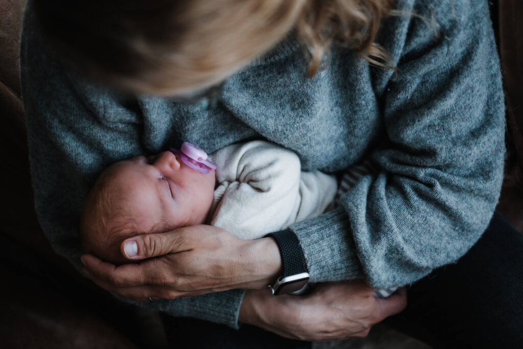 Mutter hält ihr Baby liebevoll im Arm, festgehalten von einer Familienfotografin in Flensburg.
