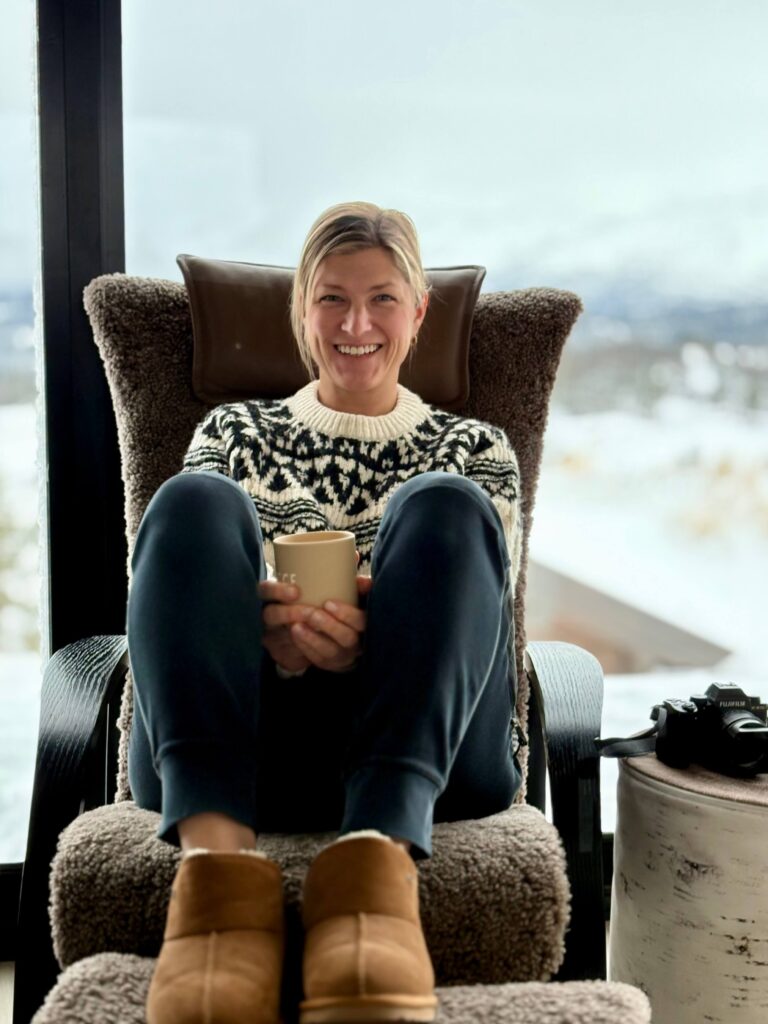 Junge Frau mit Kaffee in der Hand auf einem Sessel