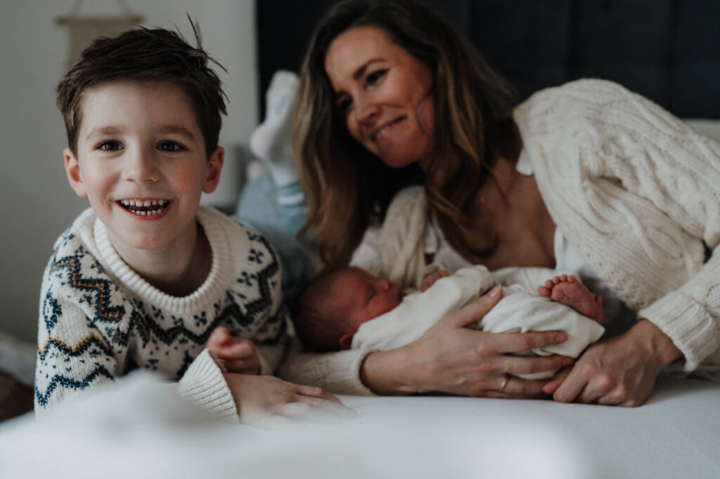 Familienmoment: Mutter, Baby und älterer Sohn im Bett – Neugeborenen Fotografin Flensburg