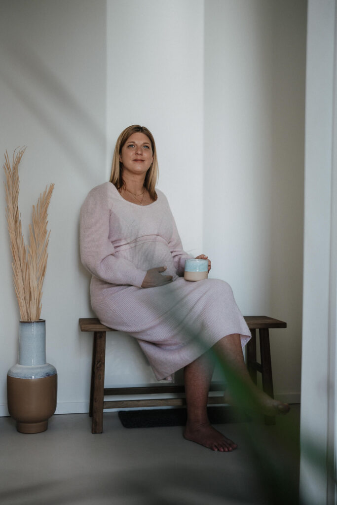 Schwangere Frau mit Kaffeebecher in der Hand