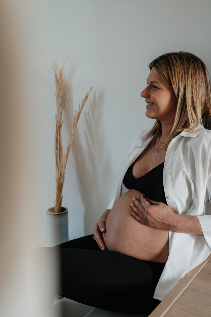 Schwangere sitzt auf einer Treppe und hält ihren Babybauch