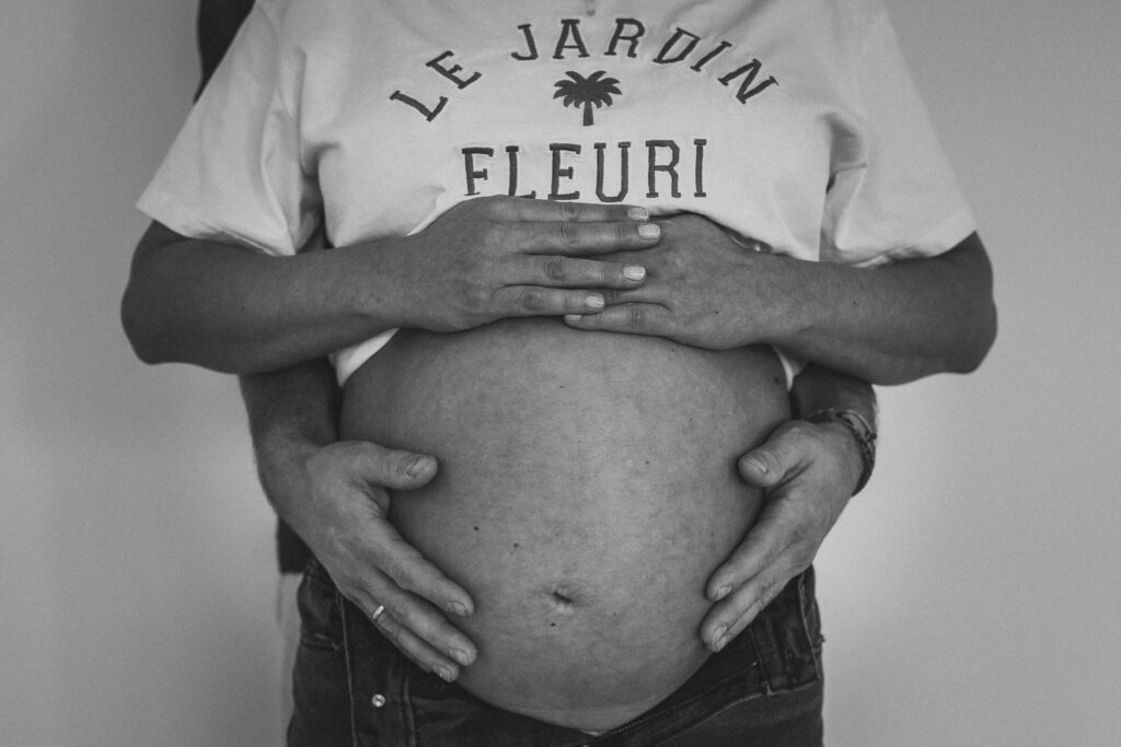 Nahaufnahme eines Babybauches mit den Händen der Mutter und des werdenen Vaters darauf