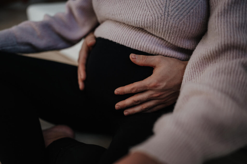 Nahhaufnahme eines Babybauchs mit den Händen des werdenden Vaters