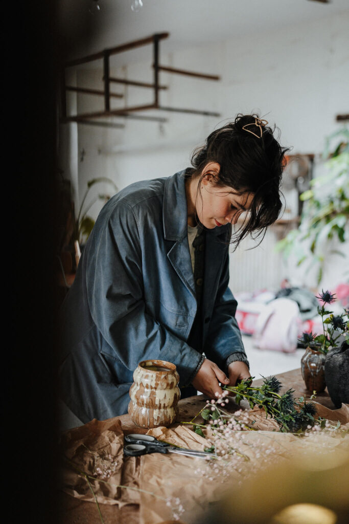 Flensburgerin arrangiert Blumen in einer selbst hergestellten Vase für ihren Online Shop