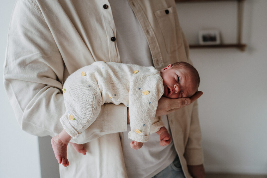 Neugeborenes bei einem Fotoshootings zu Hause in Papas Arm